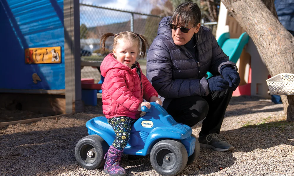 A little girl on a push bike with her childcare provider